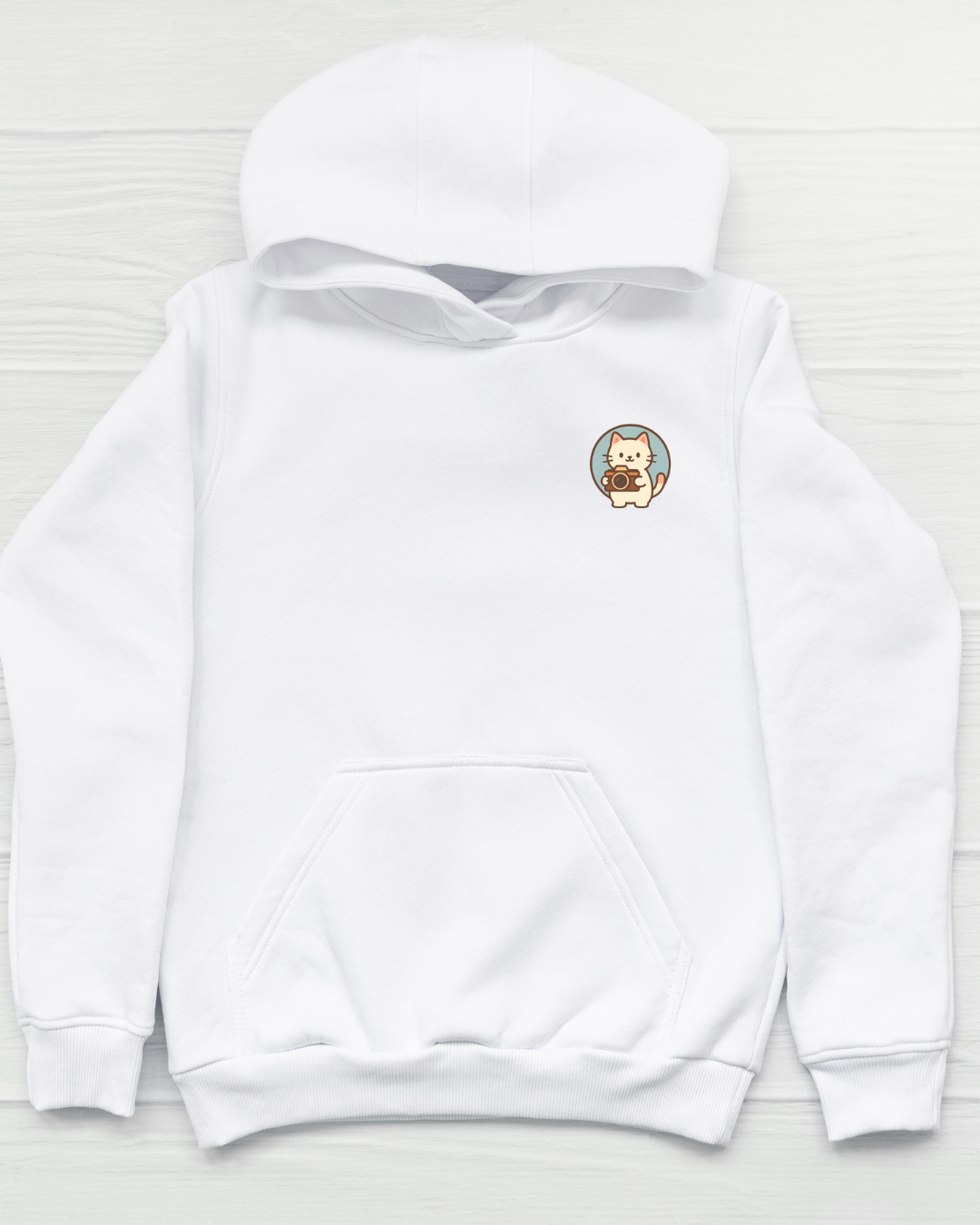 White hoodie with a small circular patch featuring a bear design on a light wooden background